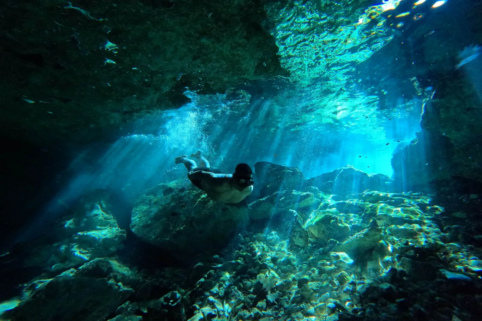 Buzo en una cueva inundada con rayos de luz entrando desde arriba