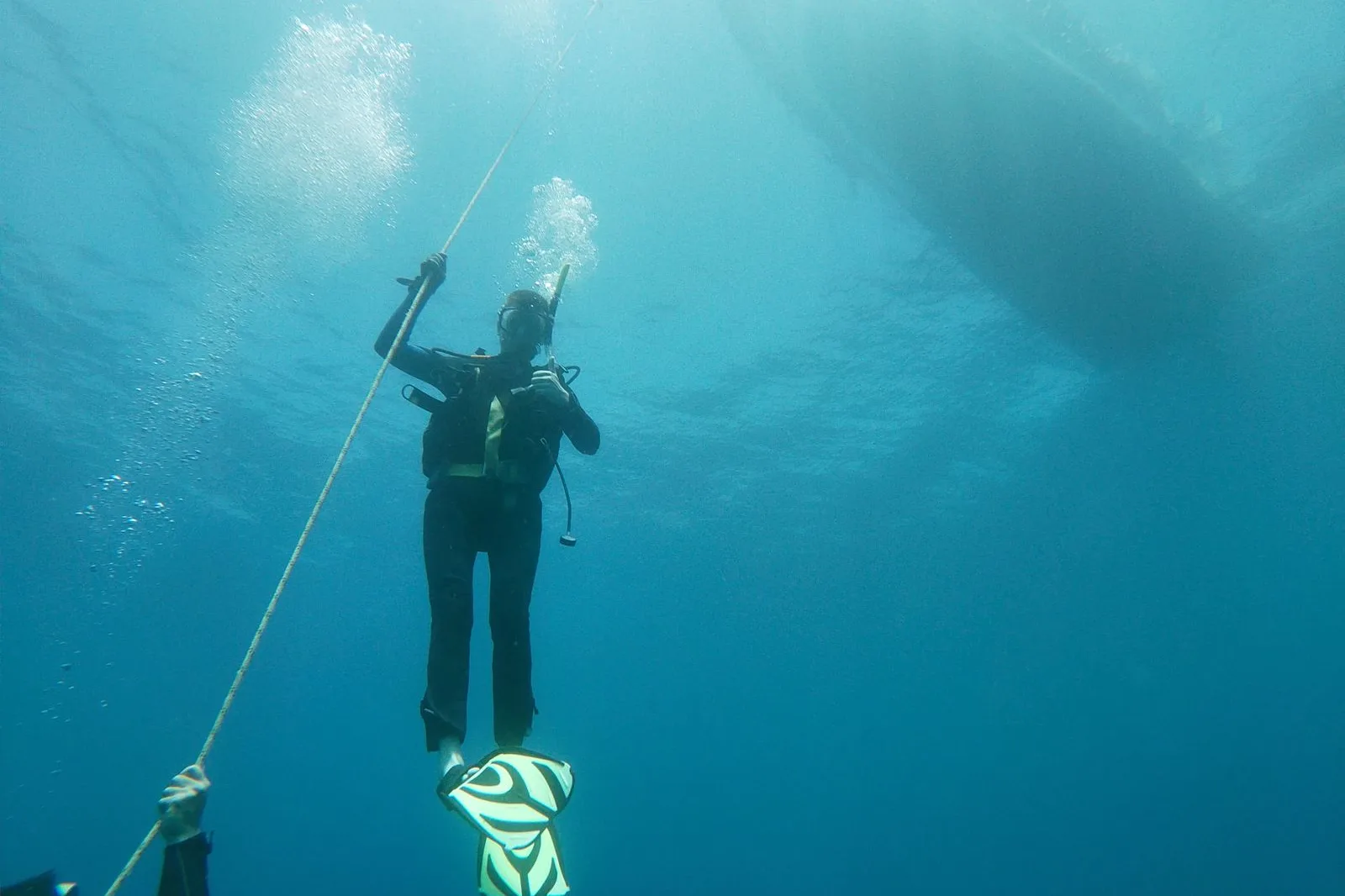 Buzo descendiendo por un cabo en agua azul